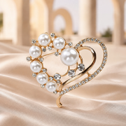 Gold-tone pearl heart brooch on champagne fabric with softly blurred arches